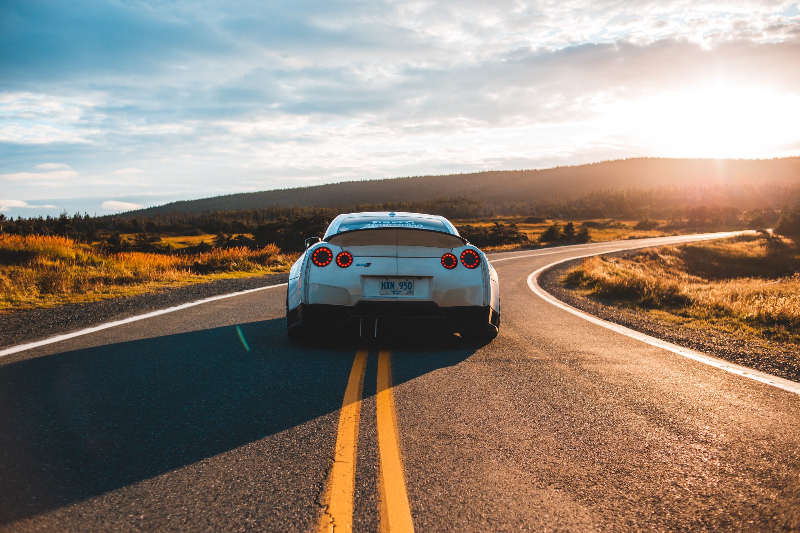 夕焼けの道路を走るスポーツカー